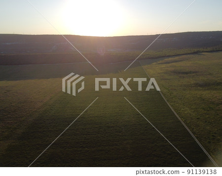 Aerial view on green wheat field in countryside. Field of wheat blowing in the wind on sunset. Young and green Spikelets. Ears of barley crop in nature. Agronomy, industry and food production. 91139138