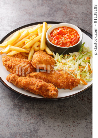 Breaded fried chicken with french fries, vegetable salad and spicy sauce close-up in a plate. vertical 91139188