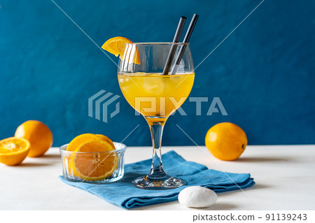 Yellow bird cocktail with rum, orange and lime juice, fruits, blue napkin on white table with dark blue background 91139243