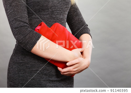 Girl having stomach ache, holding hot water bottle Girl having stomach ache, holding hot water bottle 91140395