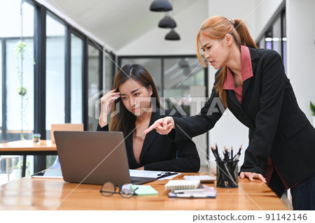 Displeased female boss scolding young intern with bad work results. Emotional pressure, stress at work 91142146