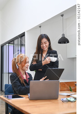 Two professionals business women discussing project developing financial research, working together in modern office Two professionals business women discussing project developing financial research, working together in modern office 91142147