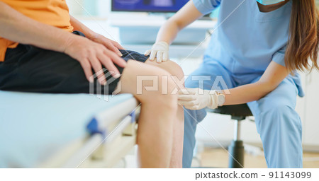 doctor examining patient knee doctor examining patient knee 91143099