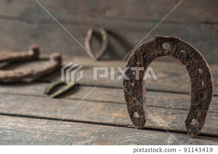Old rusty horseshoe on a wooden background Old rusty horseshoe on a wooden background 91143419