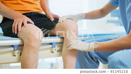 doctor examining patient knee 91145218