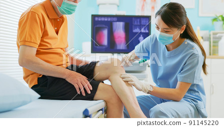 doctor examining patient knee doctor examining patient knee 91145220