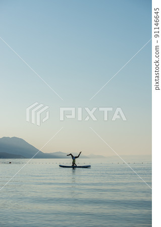 Making headstand on sup board on the sea 91146645