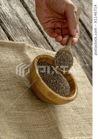 Male hand holding a wooden spoon heaping with chia seeds 91146714