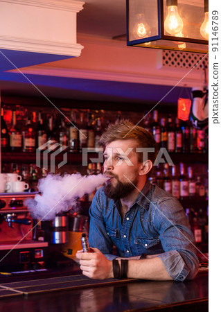 Vape. Vaping man in a cloud of vapor. Photo is taken in a vape bar. 91146789