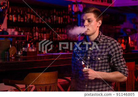 The man smoke an electronic cigarette at the vape shop. 91146805