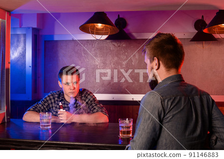 Two young men smoke electronic cigarettes in a vapebar 91146883
