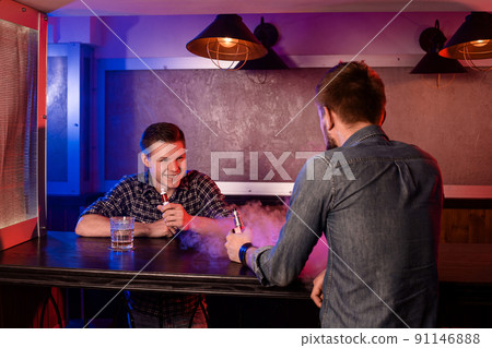 Vaping man holding a mod. A cloud of vapor at the vapebar. Vaping man holding a mod. A cloud of vapor at the vapebar. 91146888