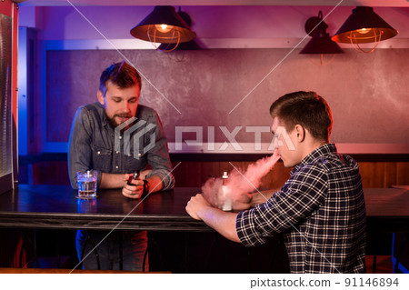 Vaping man holding a mod. A cloud of vapor at the vapebar. 91146894