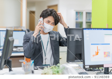 A young businessman wearing a mask and working in the office 91148369