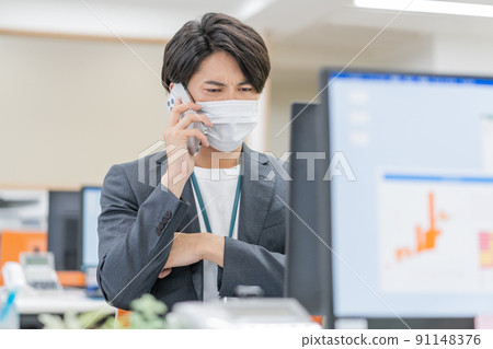 A young businessman wearing a mask and working in the office 91148376