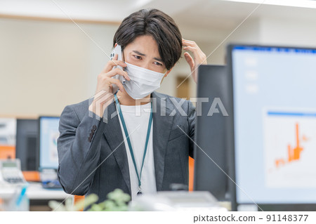 A young businessman wearing a mask and working in the office 91148377