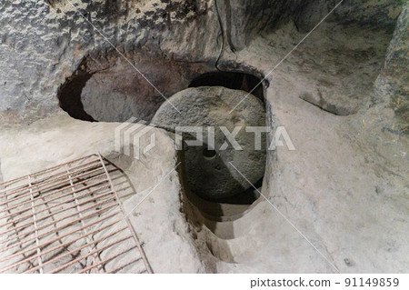 A round stone door in a cave. Cave of the 17th century Orthodox hermits. A narrow passage. 91149859