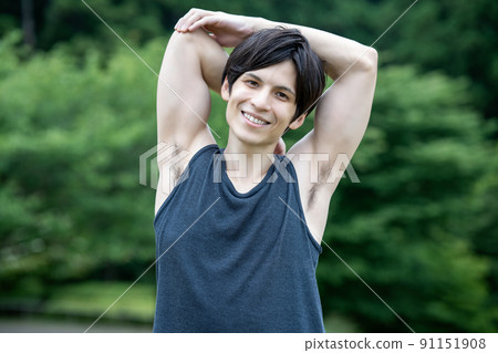 A young foreign man stretching in the fresh green 91151908