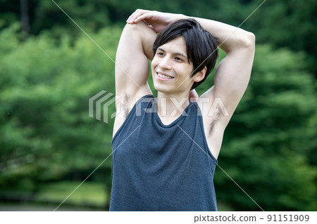 A young foreign man stretching in the fresh green 91151909