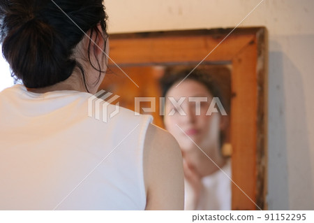 Back view of a woman looking in the mirror 91152295