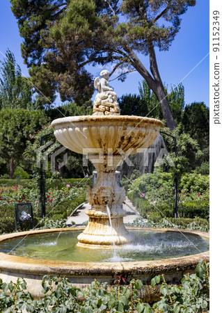 Font. Park. Roses. Stone fountain next to a park full of green vegetation and a variety of flowers of different colors in the city of Madrid, in Spain. Europe. Horizontal photography. Font. Park. Roses. Stone fountain next to a park full of green vegetation and a variety of flowers of different colors in the city of Madrid, in Spain. Europe. Horizontal photography. 91152349