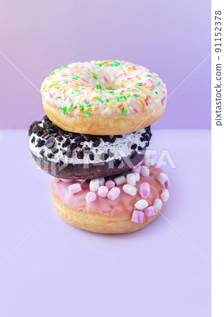 Stack of different sweet donuts with sprinkles on table Stack of different sweet donuts with sprinkles on table 91152378