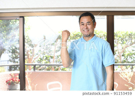 A smiling male caregiver doing a guts pose 91153459