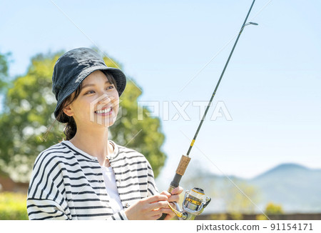 一個微笑的年輕女子（在藍天下享受釣魚的愛好）002 91154171