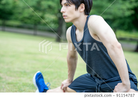 A young foreign man stretching in the fresh green 91154787