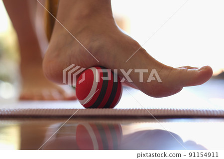 Person rolls massage ball with foot of foot closeup 91154911
