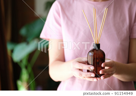 Person holds bottle of incense and aromatherapy incense sticks Person holds bottle of incense and aromatherapy incense sticks 91154949