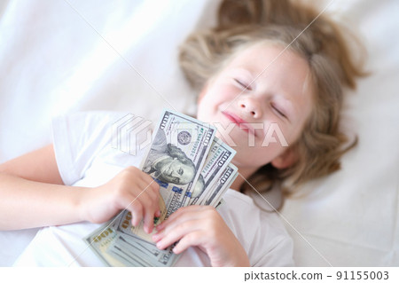 Little happy baby girl sleeps with cash dollars closeup 91155003