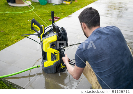 Pressure washer cleaning machine on wet concrete floor near the house build, cleaning terrace with a power washer 91156711
