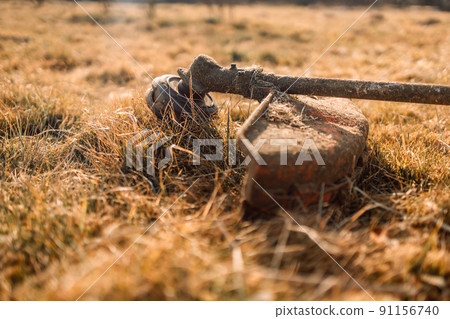 Mowing tall grass with electric or petrol lawn trimmer in city park or backyard. Mowing tall grass with electric or petrol lawn trimmer in city park or backyard. 91156740