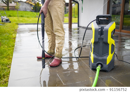 Pressure washer cleaning machine on wet concrete floor near the house build, cleaning terrace with a power washer 91156752