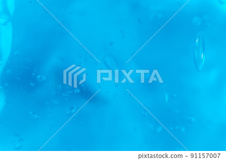Texture of transparent antiseptic gel with air bubbles on blue background. Summer ocean imitation. Concept of skin moisturizing, prevention of virus. Liquid beauty product closeup. Backdrop, flat lay 91157007