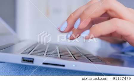 Woman hands typing on laptop computer keyboard - close up side view 91157479