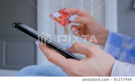 Woman using smartphone and credit card for online shopping - close up side view 91157494
