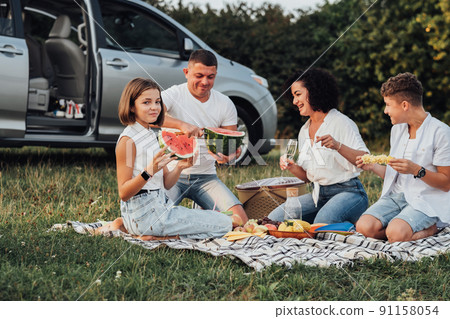 Happy Four Members Family Having Picnic at Sunset, Cheerful Mother and Father with Two Teenage Children Enjoying Weekend Road Trip by Car Happy Four Members Family Having Picnic at Sunset, Cheerful Mother and Father with Two Teenage Children Enjoying Weekend Road Trip by Car 91158054