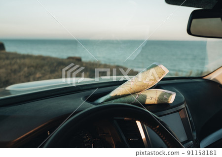 Paper Map Laying on the Dashboard of Car on the Background of Sea Paper Map Laying on the Dashboard of Car on the Background of Sea 91158181