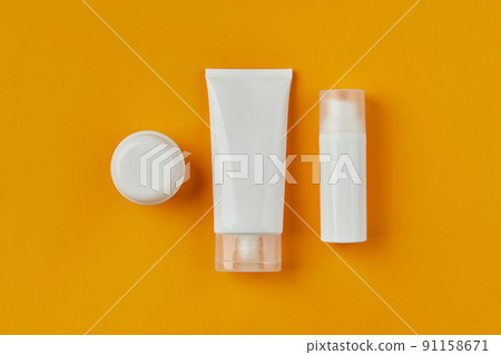 Flat lay top view blank white tubes bottles with skin care products on orange creative background 91158671