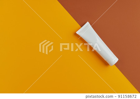 Flat lay top view blank white tube bottle with lotion cream or cleanser on orange background Flat lay top view blank white tube bottle with lotion cream or cleanser on orange background 91158672
