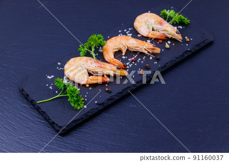 Big raw red prawns with parsley, salt and pepper on a slate board on black background 91160037