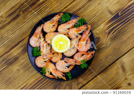 Red boiled prawns with lemon and parsley on wooden table. Top view 91160039