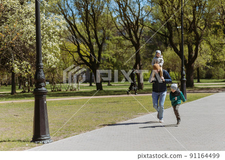A father running down the lane with his two sons. spending time with kids on fresh air in autumn time. 91164499