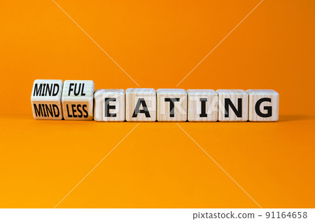 Mindful or mindless eating symbol. Turned wooden cubes and changed words mindless eating to mindful eating. Beautiful orange background, copy space. Medical and mindful or mindless eating concept. 91164658