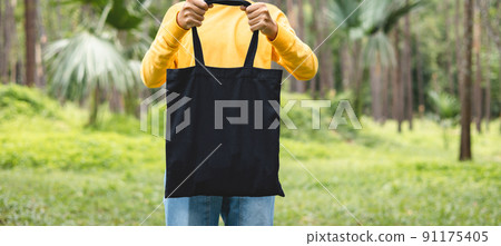 woman holding black cotton bag in nature background 91175405