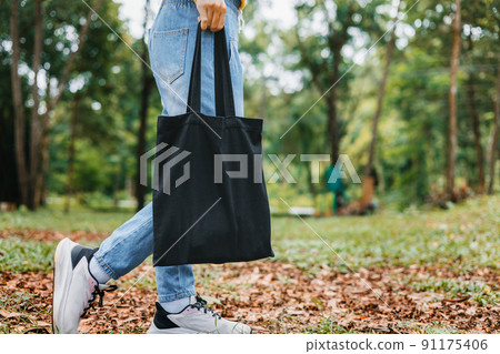 woman holding black cotton bag in nature background 91175406