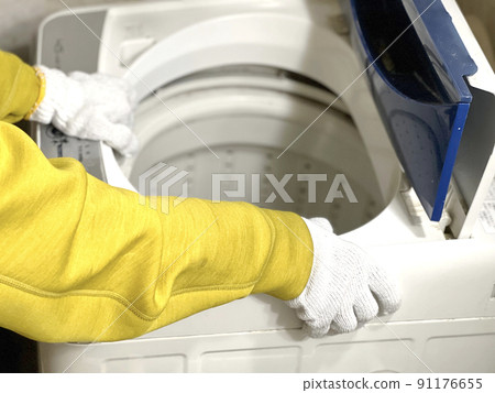 Hands with gloves carrying a washing machine 91176655