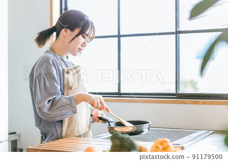 Female using a frying pan in the kitchen (tired) Female using a frying pan in the kitchen (tired) 91179500